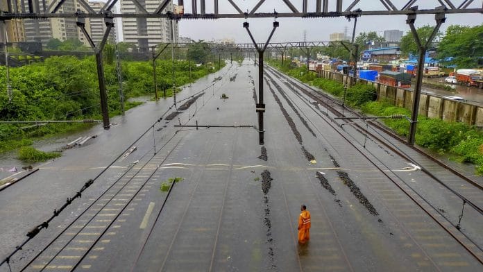 A man stands on waterlogged railway tracks between Kurla and Sion, following heavy rainfall, in Mumbai | PTI