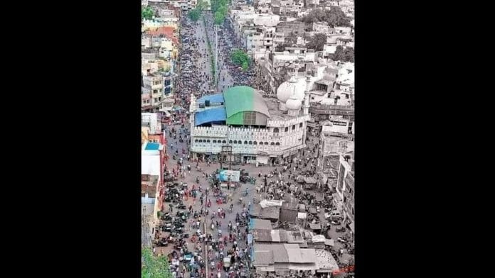 A mosque in the middle of the road located in a crowded area from Madhya Pradesh