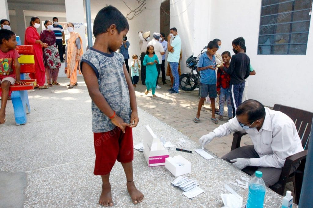 A young kid looking at the testing kid in Sahnewal village | Praveen Jain | ThePrint