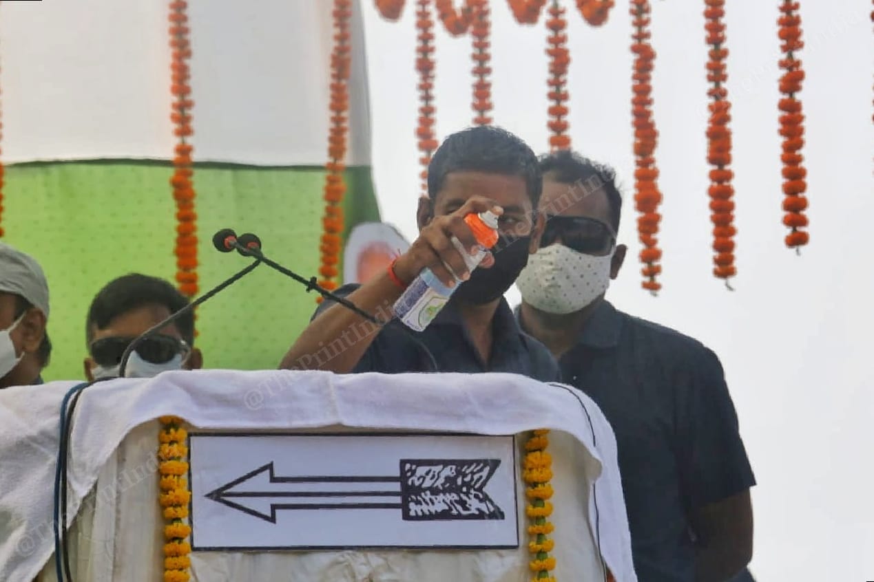 A security personnel sprays sanitiser on the podium and the mic before the chief minister's speech | Photo: Praveen Jain | ThePrint