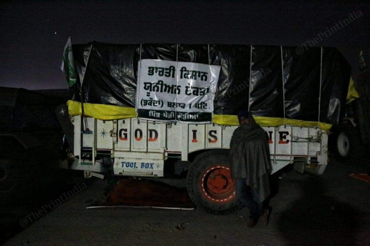A farmer stands near one of the tractors where it is written " God is one" | Photo: Manisha Mondal | ThePrint