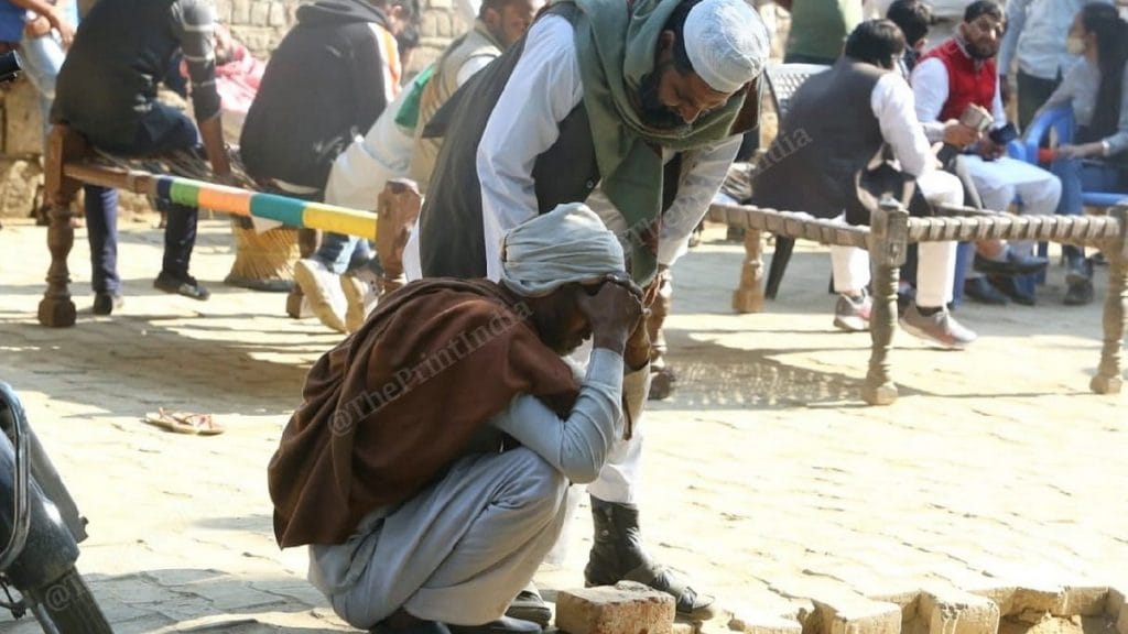 Khurshid (squatting) is consoled by a relative in his village | Photo: Praveen Jain | ThePrint