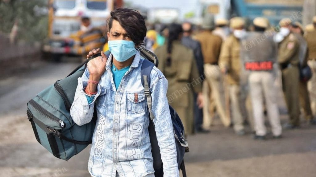A commuter walks across the Singhu border with luggage | Photo: Manisha Mondal | ThePrint
