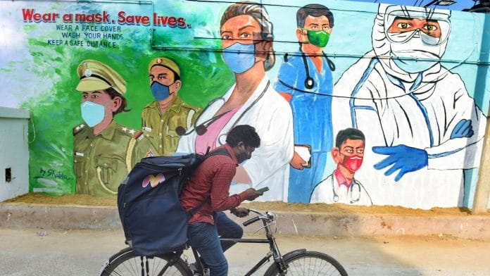 A cyclist rides past a mural honouring Covid warriors, in New Delhi | PTI