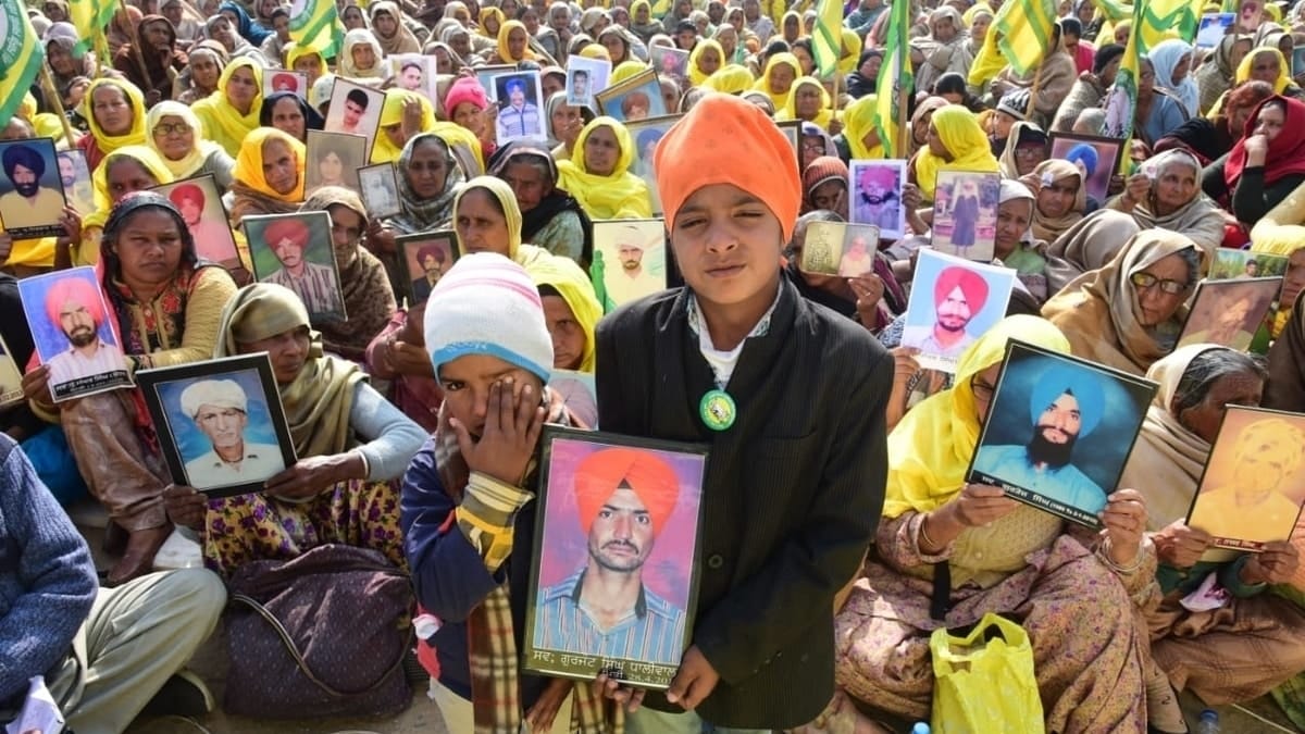 Women and children holding frames of their farmer family members who died by suicide. | Photo: Special arrangement