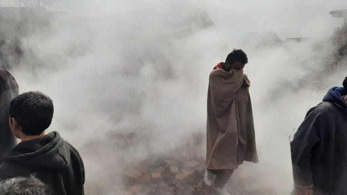 A Rawalpora resident stands amid smoke from the gutted remains of some local homes | Azaan Javaid | ThePrint