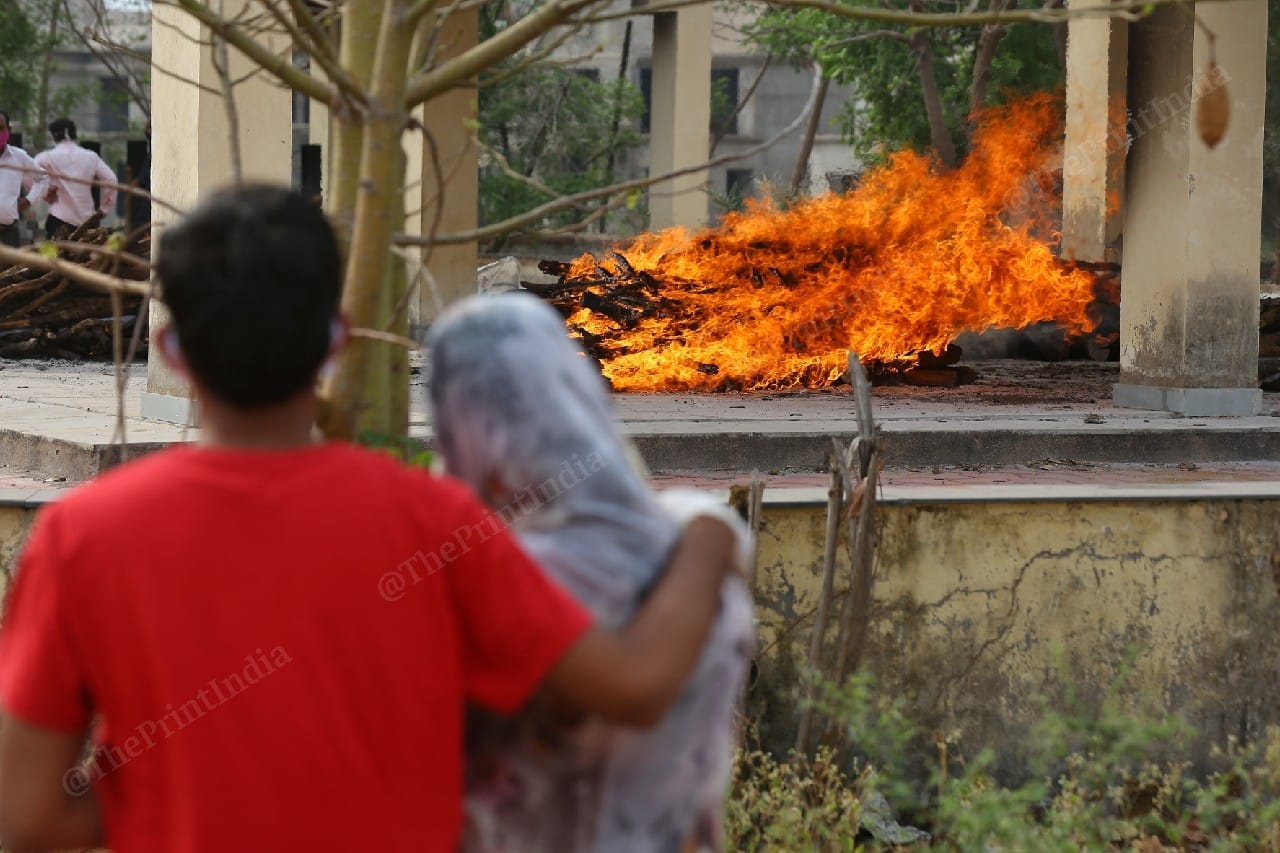 A Covid patient's family watches on the funeral pyre of their family member. | Photo: Suraj Singh Bisht/ThePrint