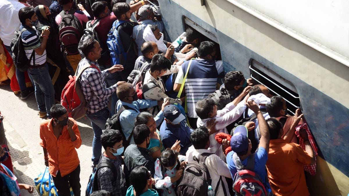 Distancing norms go for a toss as passengers rush to board a train at Patna junction on the eve of Holi in March | ANI