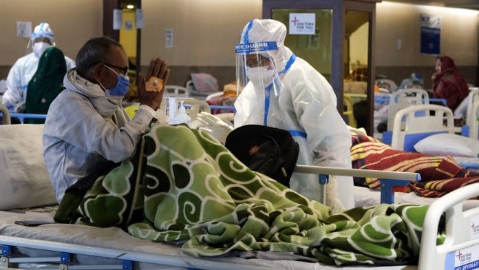 A health workers in personal protective equipment (PPE) assists a patient at a makeshift Covid-19 quarantine facility set up in a banquet hall in New Delhi | Bloomberg
