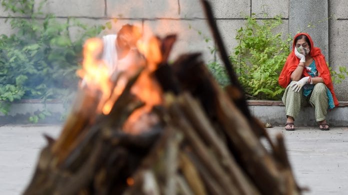 A family member looks on during the cremation of a person who died of Covid, at the Seemapuri Cremation Grounds, in New Delhi on 16 April 2021 | PTI Photo