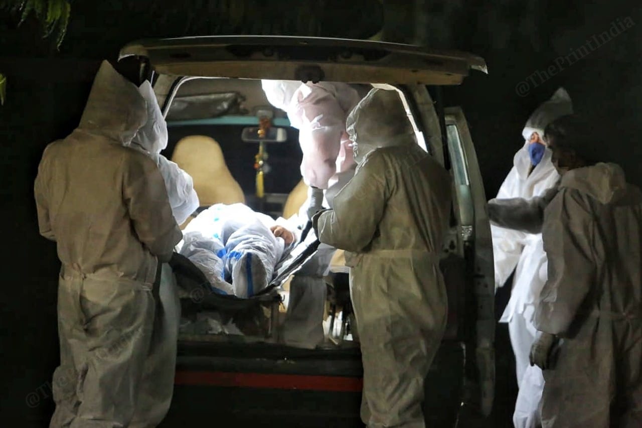 Crematorium workers, donning PPE suits, take a body out of a van for cremation at Hatkeshwar | Photo: Praveen Jain | ThePrint