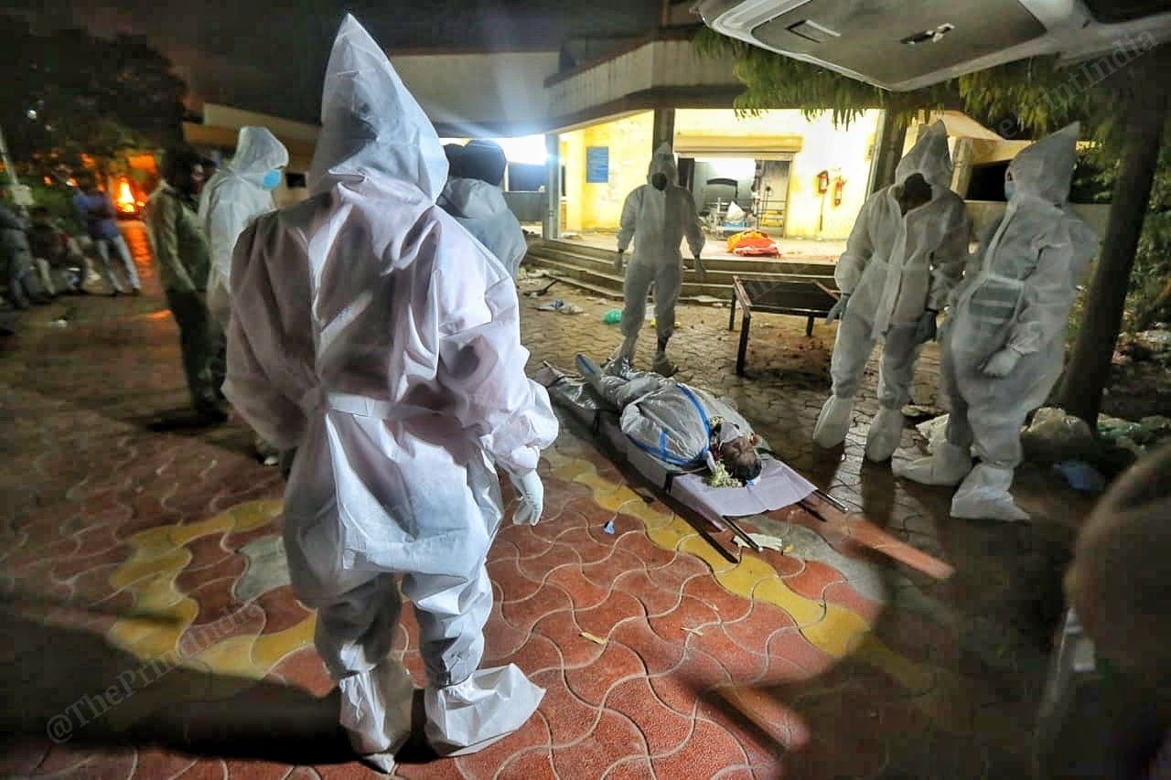 PPE clad crematorium workers gather around a body | Photo: Praveen Jain | ThePrint