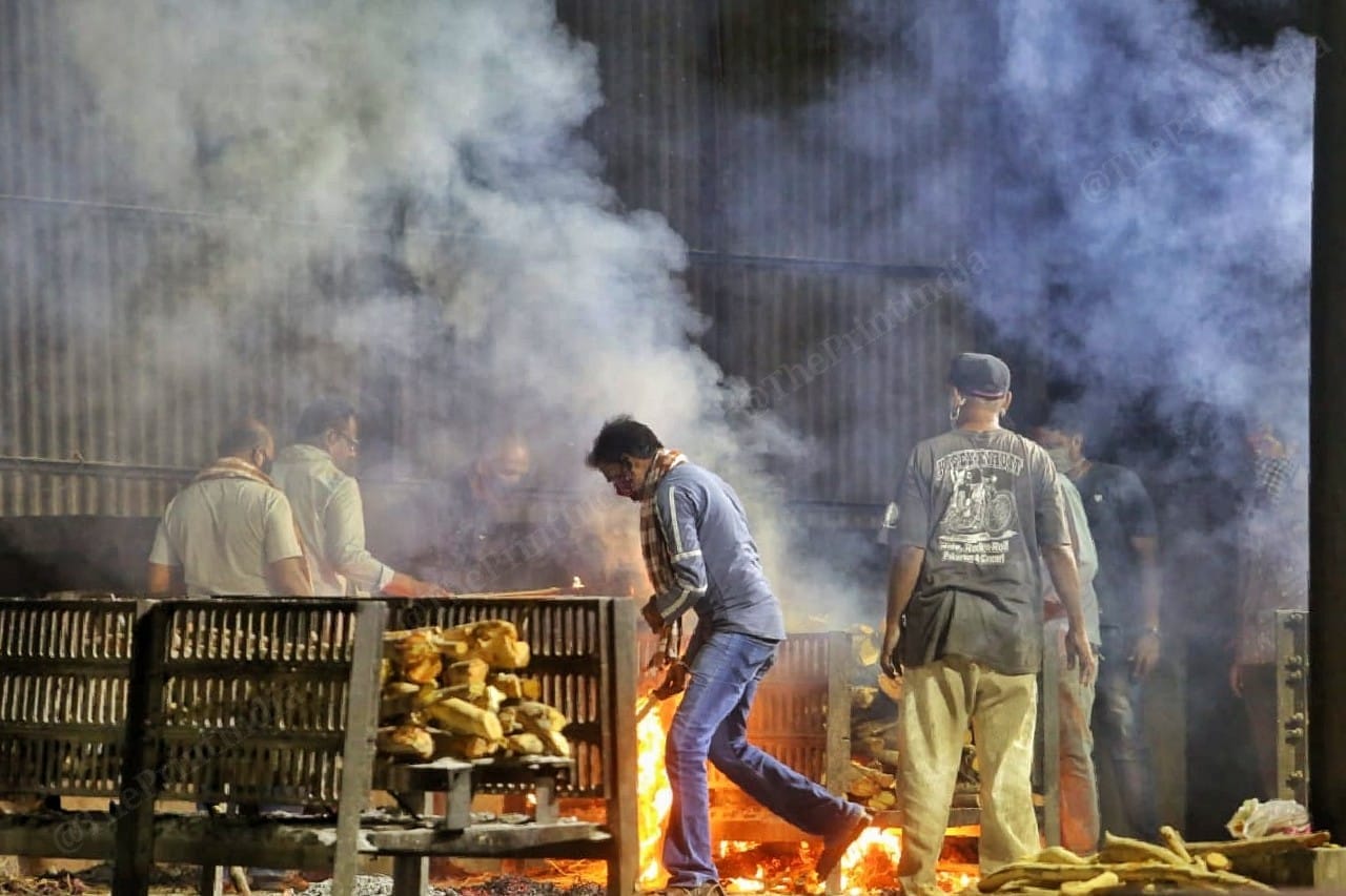 A family member of the deceased lights up the pyre of their deceased family memeber at Hatkeshwar crematorium | Photo: Praveen Jain | ThePrint