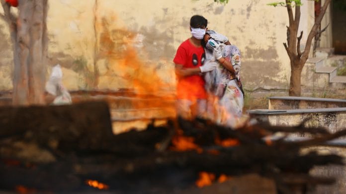 A Covid patient’s family members watch the funeral pyre | Photo: Suraj Singh Bisht |ThePrint