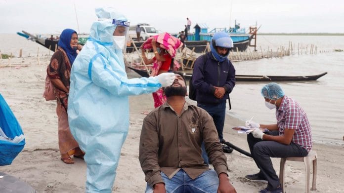 A health worker takes a swab sample of a passenger for Covid test at Dakhinpat ghat on the bank of the river Brahmaputra in Majuli District of Assam, on 15 May 2021 | PTI