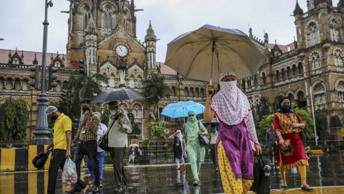 People wearing protective masks cross a road outside Chhatrapati Shivaji Maharaj Terminus (CST) railway station in Mumbai | Photographer: Dhiraj Singh | Bloomberg