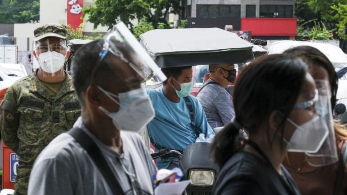 A Philippine Army soldier observes motorcycle taxi drivers waiting in line at a Covid-19 drive-thru vaccination site set up at the Philippine International Convention Center in Manila | Photographer: Veejay Villafranca | Bloomberg