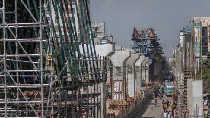 Pedestrians and cyclists pass an under-construction elevated line for the Dhaka Mass Rapid Transit Co. metro in Dhaka in 2019 | Photo: Ismail Ferdous | Bloomberg File Photo