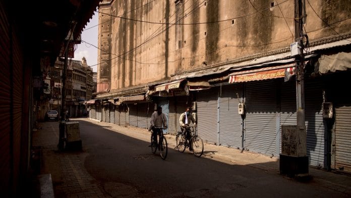 Cyclists ride past closed stores in a deserted market area during lockdown restrictions in Agra, on 6 June 2021 | Bloomberg photo