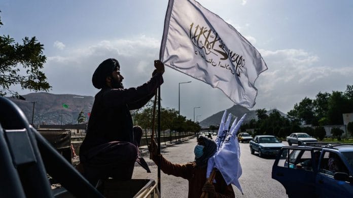 A boy selling Taliban flags brings his ware towards a military vehicle in Kabul on 20 August 2021 | Marcus Yam | Bloomberg via Getty Images