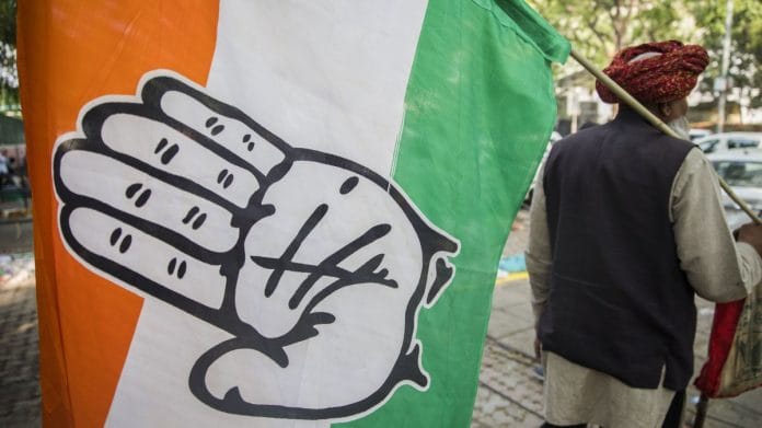 A Congress supporter carries its flag outside the party's headquarters in New Delhi | File photo | Photographer: T. Narayan | Bloomberg