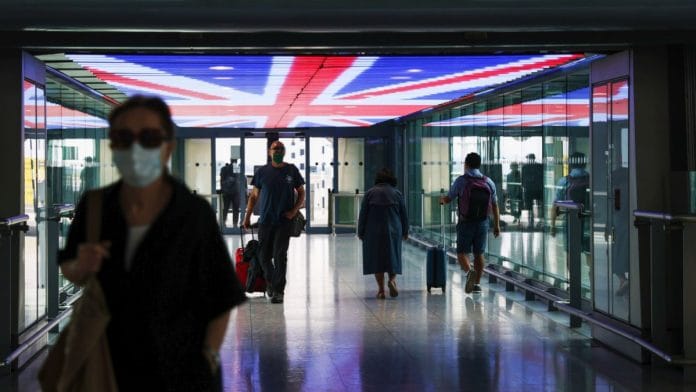 Travellers walk underneath a British Union Flag at Terminal 5, London Heathrow Airport Ltd. in London Photographer: Hollie Adams | Bloomberg