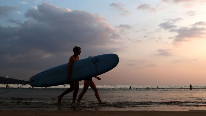 Tourists with a surfboard walk along Dewata Beach in Galle, Sri Lanka | Buddhika Weerasinghe | Bloomberg