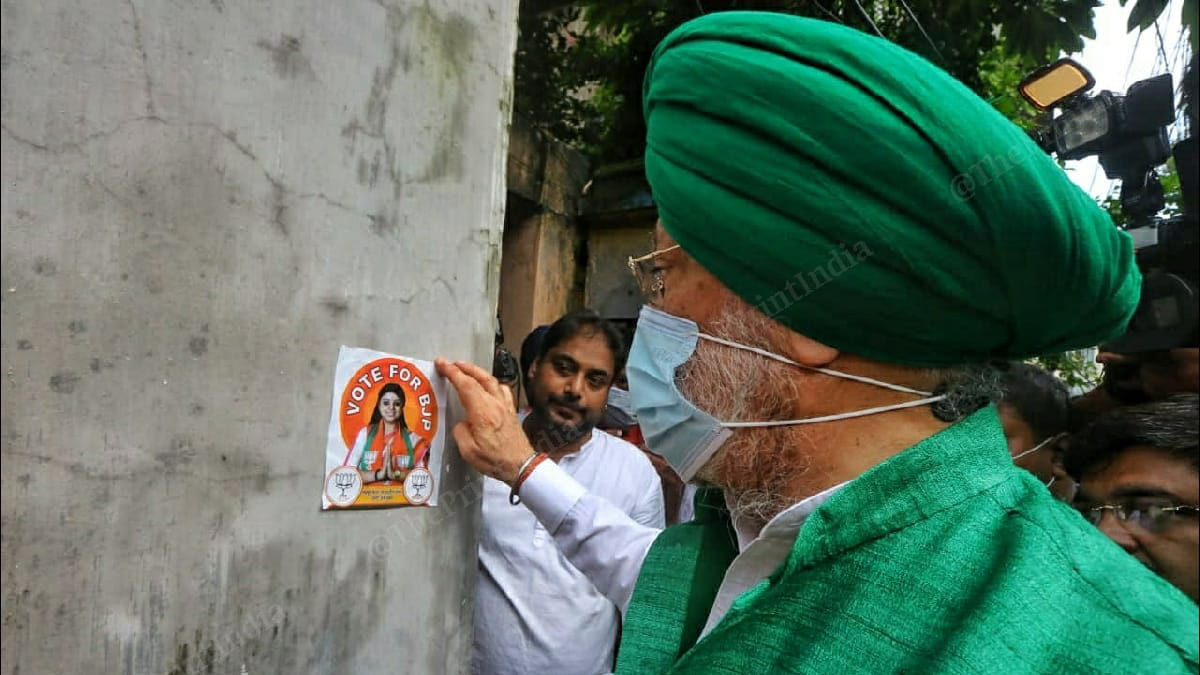 Union Minister Hardeep Singh Puri putting up a poster of Priyanka Tibrewal, the BJP candidate, in Bhabanipur | Praveen Jain, ThePrint