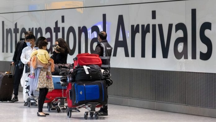 Passengers, wearing protective face masks, walk through the international arrivals hall after arriving in Terminal 5 at London Heathrow Airport in London, UK | Photographer: Jason Alden | Bloomberg