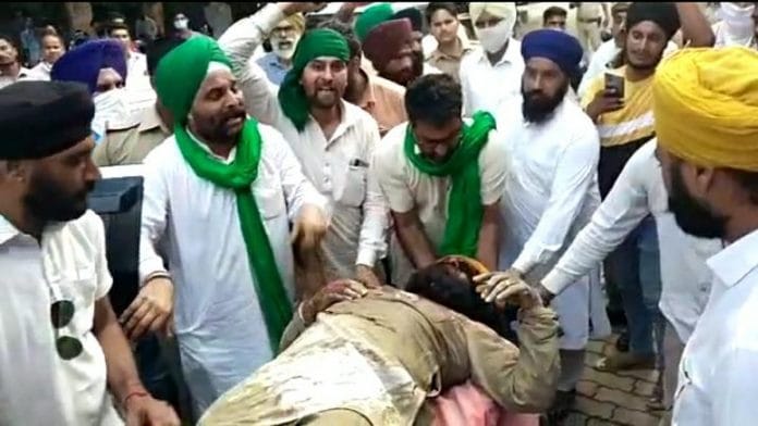 Protesters surround a man allegedly injured during the clash at Lakhimpur Sunday | By special arrangement