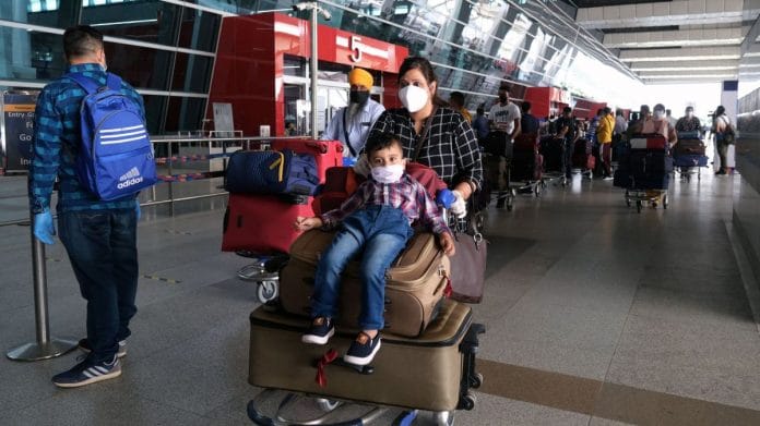 Travellers wearing protective masks wait in line at the drop-off point to enter Terminal 3 of the Indira Gandhi International Airport in New Delhi | Photographer: Arco Dato | Bloomberg