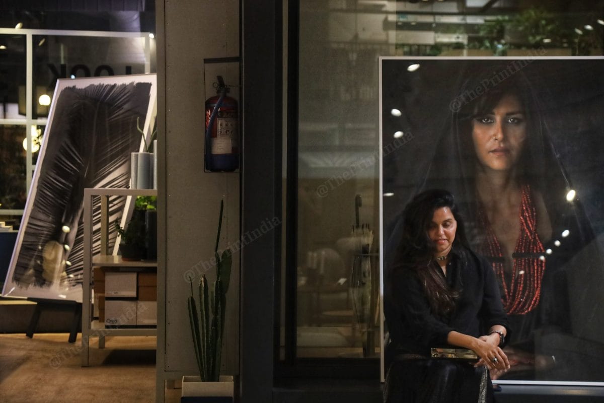 A woman sits poses for a photo with one of the photographs | Photo: Manisha Mondal | ThePrint