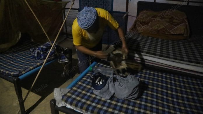 A fellow protester wraps up Gurpreet Singh's belongings after his alleged suicide at Singhu border Wednesday | Manisha Mondal | ThePrint