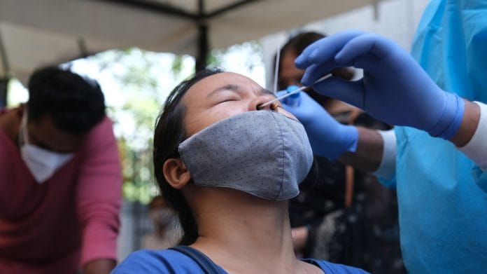 A medical worker collects sample for Covid-19 testing in New Delhi on 21 October 2021 | Bloomberg