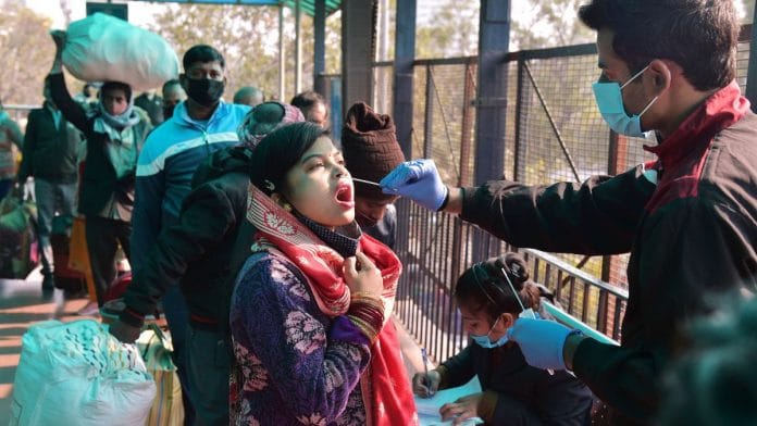 A health official takes a swab sample for Covid-19 testing at New Delhi Railway station amid concern over rising Omicron cases, on 27 December 2021 | PTI