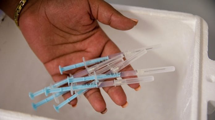 A health worker handles prepared doses of the Pfizer-BioNTech Covid vaccine at the Grassy Park civic center in Cape Town, South Africa | Bloomberg