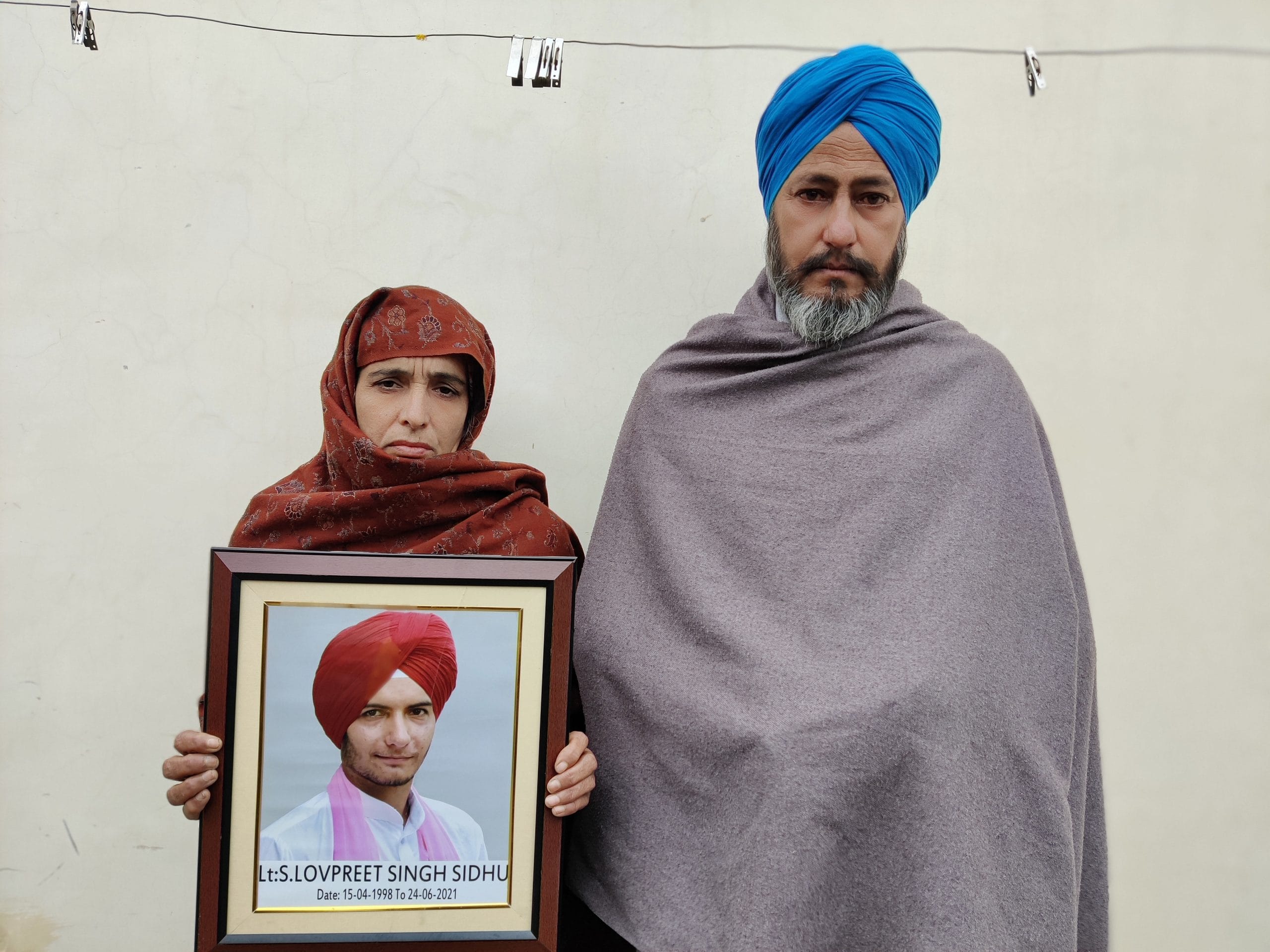 Parents of Lakhwinder Singh 'Ladi' stand with his photograph at their house. Ladi drank fertilizer and killed himself after he was abandoned by his wife | Shubhangi Misra | ThePrint 