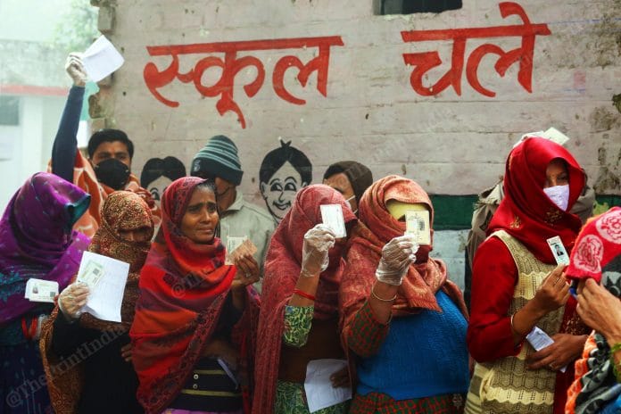 Voters standing in queue showing their ID cards before cast their vote at a polling booth in Baroli Village Baraut | Praveen Jain | ThePrint