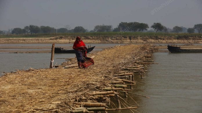 A woman crosses a makeshift temporary bridge that villagers built in Kakra Ghat, Shravasti district, UP | Photo: Manisha Mondal/ThePrint
