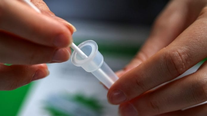A swab from a Covid lateral flow self-test kit in a buffer solution vessel arranged in Danbury, UK | Representational image | Bloomberg