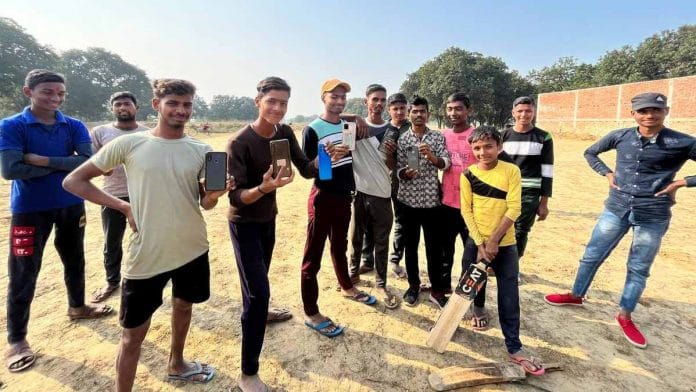 A group of young men pose with their phones in Dharampur Urf Dhurwa, Prayagraj district | Photo: Jyoti Yadav/ThePrint