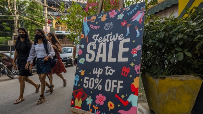 Pedestrians pass a sale sign outside a clothing store in Hauz Khas Village in New Delhi