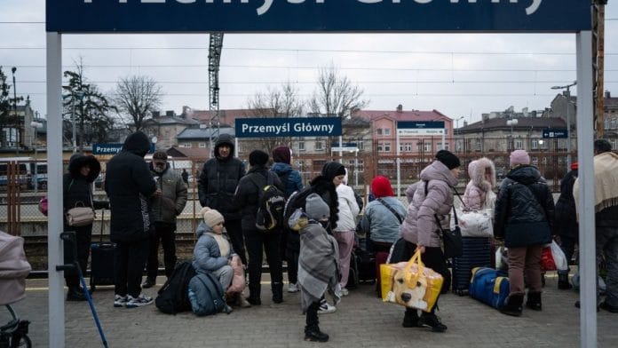 Displaced Ukrainians wait at a railway station after crossing the border into Poland, on 8 March 2022 | Bloomberg