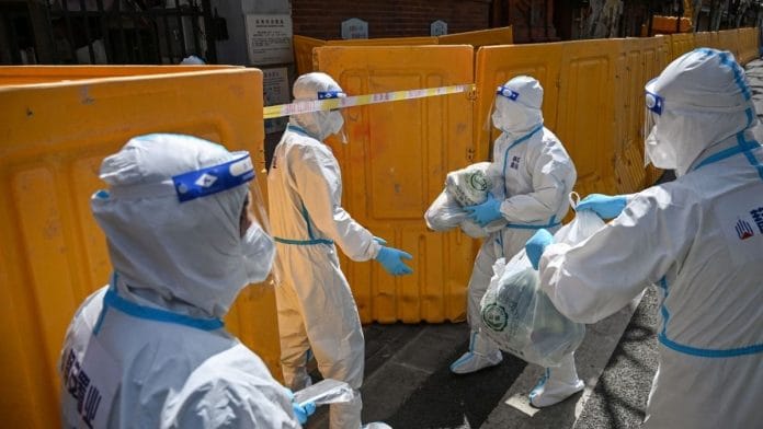 Workers from a public service organisation wearing protective gear deliver vegetables to residents of a neighborhood in lockdown in Shanghai, on 29 March 2022 | Photographer: Hector Retamal/AFP/Getty Images via Bloomberg