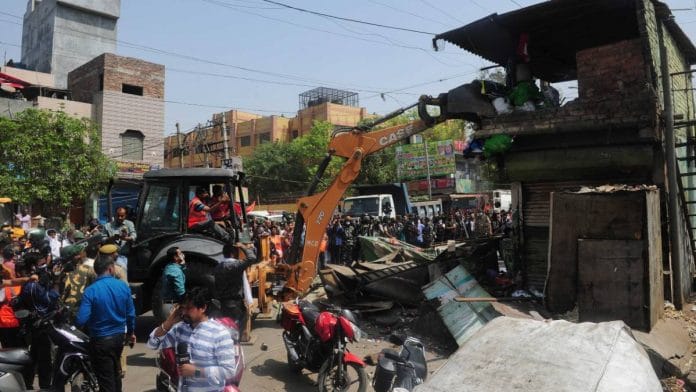 A bulldozer razes structures in the area that saw communal violence during a Hindu religious procession on Saturday at Jahangirpuri, New Delhi | Photo: Suraj Singh Bisht | ThePrint