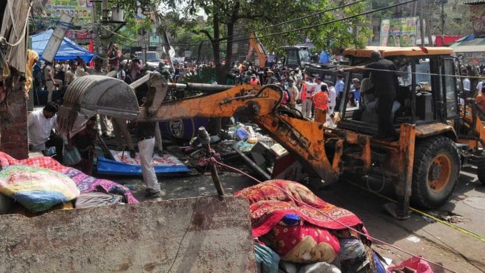 A bulldozer razes structures in the area that saw communal violence during a Hindu religious procession on Saturday at Jahangirpuri, New Delhi | Photo: Suraj Singh Bisht | ThePrint