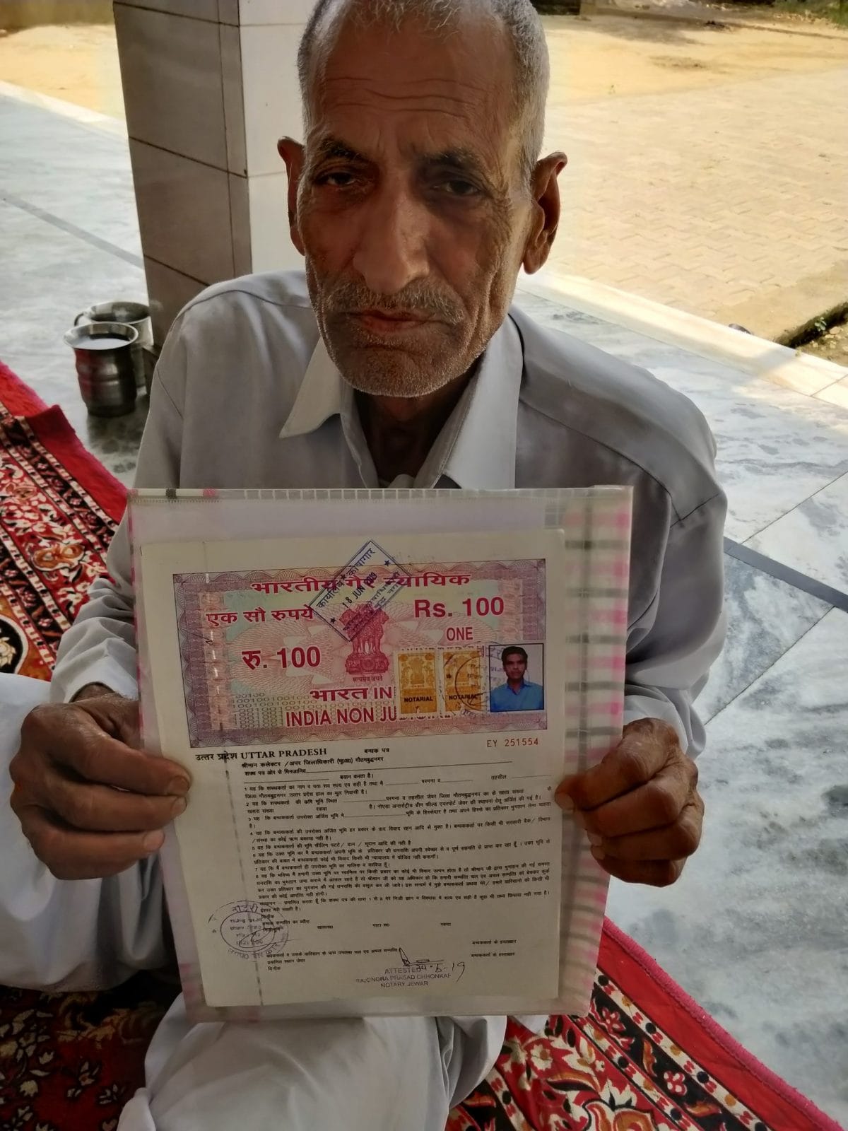 Shri Ram Singh at the Dayanatpur village temple, showing his land papers. | Photo Credit: Sonal Matharu