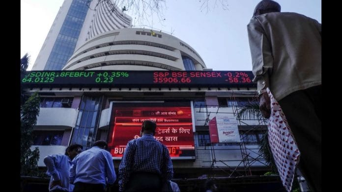 Pedestrians look up at an electronic ticker board showing a budget news report outside the Bombay Stock Exchange (BSE) in Mumbai | Bloomberg