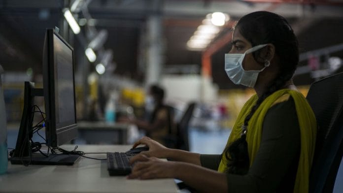 A worker wearing a protective mask works on a computer at a Flipkart warehouse in Koduvalli, Thiruvallur | Representational image | Bloomberg
