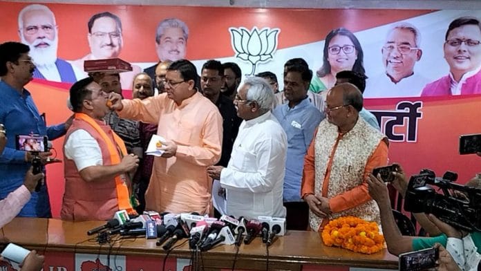 Uttarakhand CM Pushkar Singh Dhami offers a sweet to former AAP state unit chief Deepak Bali during his induction into the party | Photo: Twitter/@TheDeepakBali